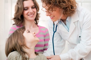 Mature doctor examining happy child, smiling.